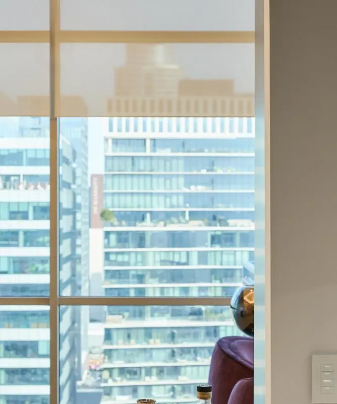 Window with a roller shade partly lowered and a Lutron keypad on the wall